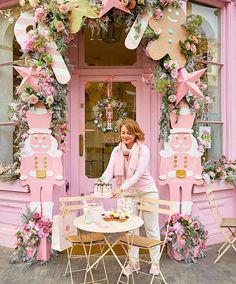 a woman sitting at a table in front of a pink building with decorations on it