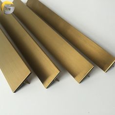 four brass colored metal bars on a white surface