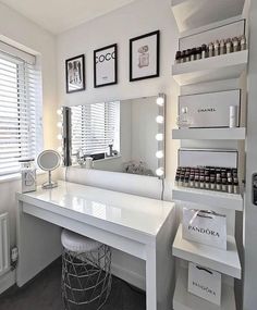 a white vanity with lots of lights on top of it and a mirror in the corner