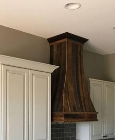 a kitchen with white cabinets and a wooden stove hood