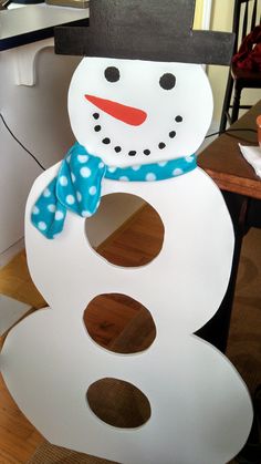 a cardboard snowman sitting on top of a wooden table