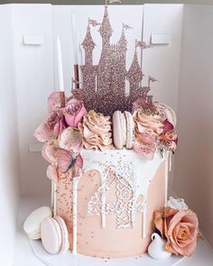 there is a cake with pink frosting and decorations on the top, surrounded by flowers