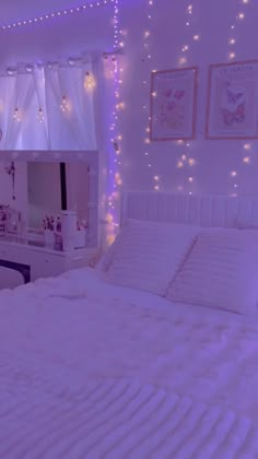 a white bed sitting in a bedroom next to a window with fairy lights on it