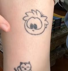 a person with a cat tattoo on their leg and another one has a face drawn on it