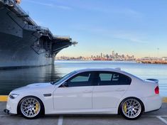 a white car parked in front of a large ship