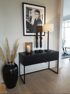 a black table with two candles on it next to a framed photograph and a vase