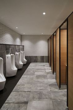 a row of urinals in a public restroom with tiled walls and flooring