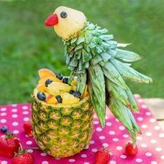 a pineapple with fruit in the shape of a bird sitting on top of it