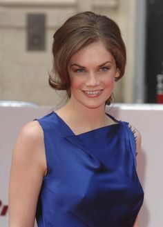 a woman in a blue dress is smiling for the camera while standing on a red carpet