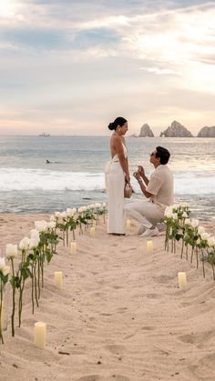 two people kneeling down in the sand with candles around them