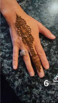 a woman's hand with henna on it and a ring in the middle