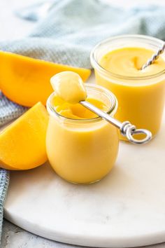 two small jars filled with orange custard on top of a white marble plate