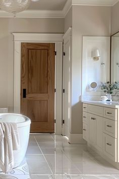 a bathroom with a tub, sink and mirror in it's center wall is shown