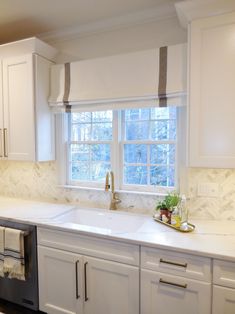 a kitchen with white cabinets and marble counter tops, along with a dishwasher