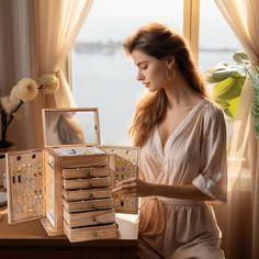 a woman sitting in front of a window holding a wooden jewelry box