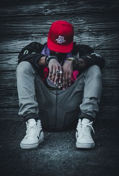 a person sitting on the ground wearing a red hat