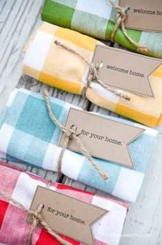 four folded napkins tied with twine and labeled welcome home tags are sitting next to each other