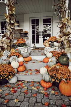 pumpkins and gourds are arranged on the front porch for fall decorating