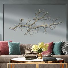 a living room filled with furniture and a large metal branch wall art above the couch