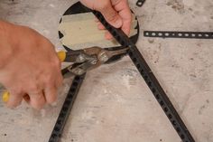 a person cutting up pieces of paper with pliers on the floor next to them