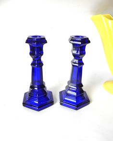 two blue glass candlesticks sitting next to each other on a white table top