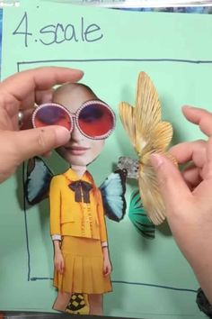 two hands holding up a paper cutout of a girl with sunglasses and a butterfly