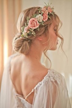 a woman with flowers in her hair wearing a white dress and veil over her shoulder