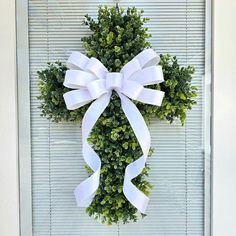 a wreath with white ribbon hanging on the front door