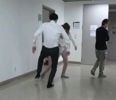 three people are dancing in an office hallway