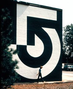 a person walking past a large black and white sign