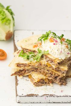 a stack of food sitting on top of a white plate next to lettuce