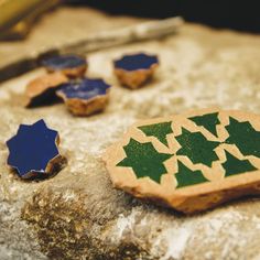 some wooden pieces with green and blue designs sitting on top of a stone slab next to other items