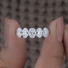 a woman's hand holding a ring with three diamonds on it and the middle one is white gold