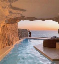 an indoor swimming pool in the middle of a cliff overlooking the ocean at sunset or dawn