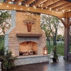 an outdoor fireplace with lights and potted plants