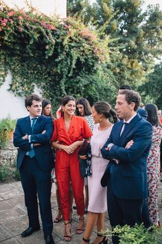 a group of people standing next to each other in front of some bushes and trees