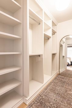 an empty walk in closet with white shelves