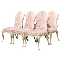 a set of four chairs with pink upholstered back and gold trimmings