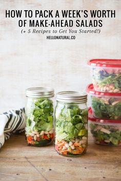 four mason jars filled with salads sitting on top of a wooden table next to each other