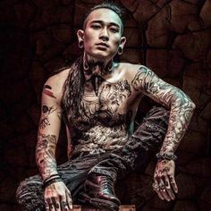 a tattooed man sitting on top of a wooden box