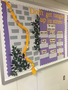 a bulletin board is decorated with yellow flowers and greenery, along with an orange tassel