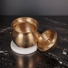 two brass bowls sitting on top of a marble counter