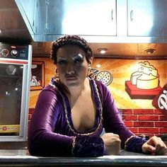 a woman sitting at a counter in front of a stove top oven with an eye patch on her face