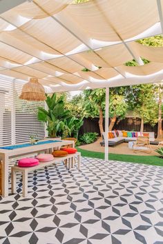 an outdoor patio with white and black tiles on the floor, tables and chairs in the background