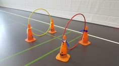 three orange traffic cones sitting next to each other on top of a track in an indoor gym