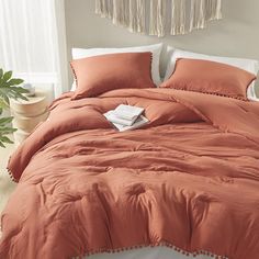 an orange comforter with pom poms on the bottom and two pillows in front