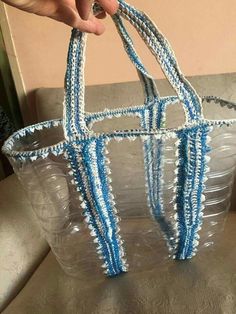 a hand holding a plastic bag made out of blue and white beads on top of a table