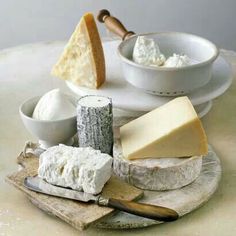 various cheeses and bread on a plate with butter in small bowls next to them