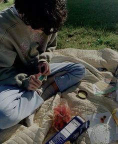 a young man sitting on top of a blanket