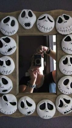 a person taking a selfie in front of a mirror decorated with fake skulls and faces